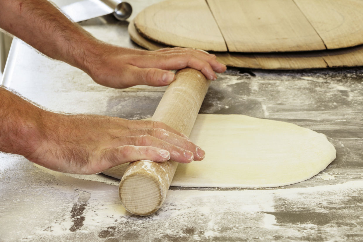 pizzaiolo étalant une pate à pizza